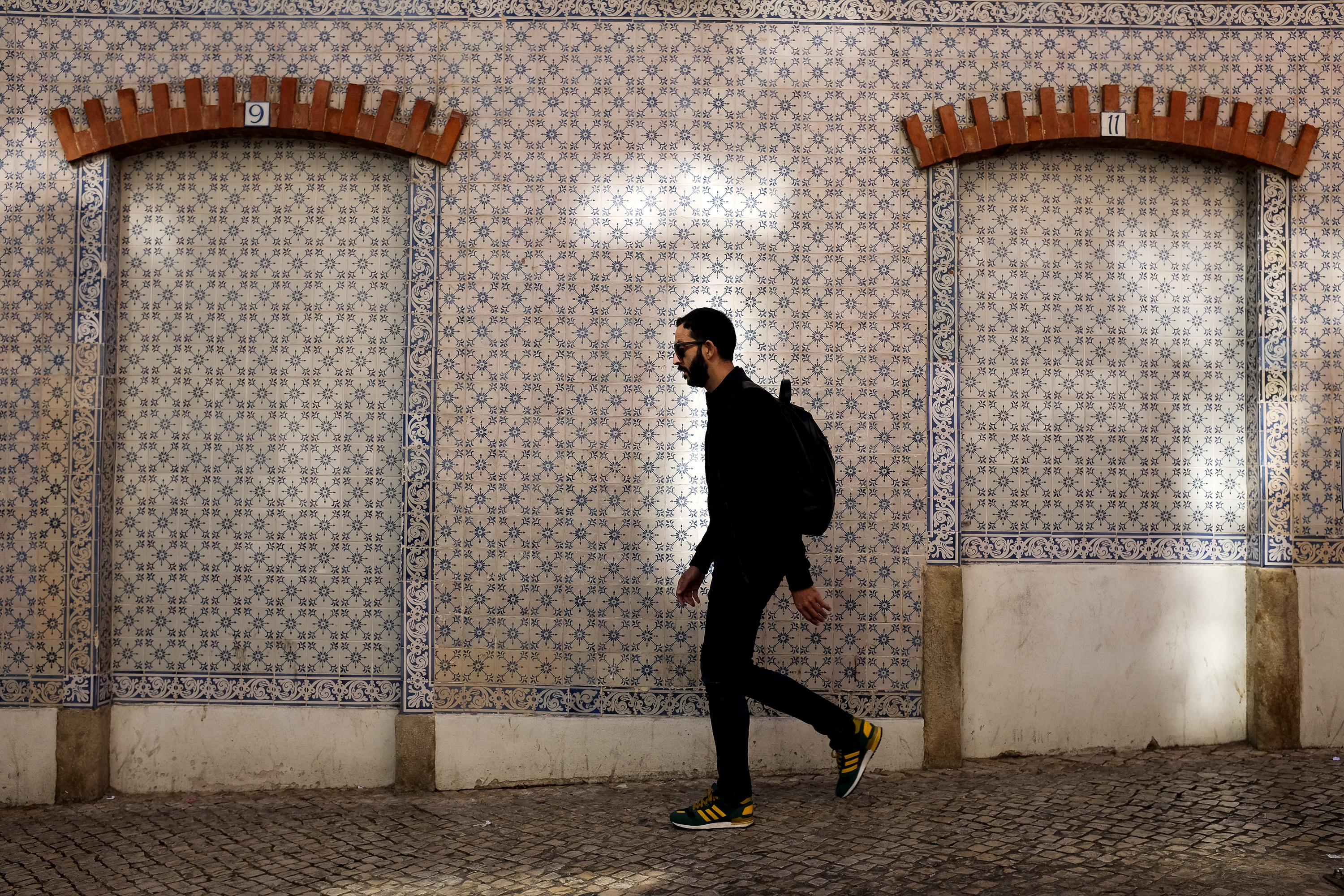 A random person walking downwards with a building frontage covered in tiles in the background