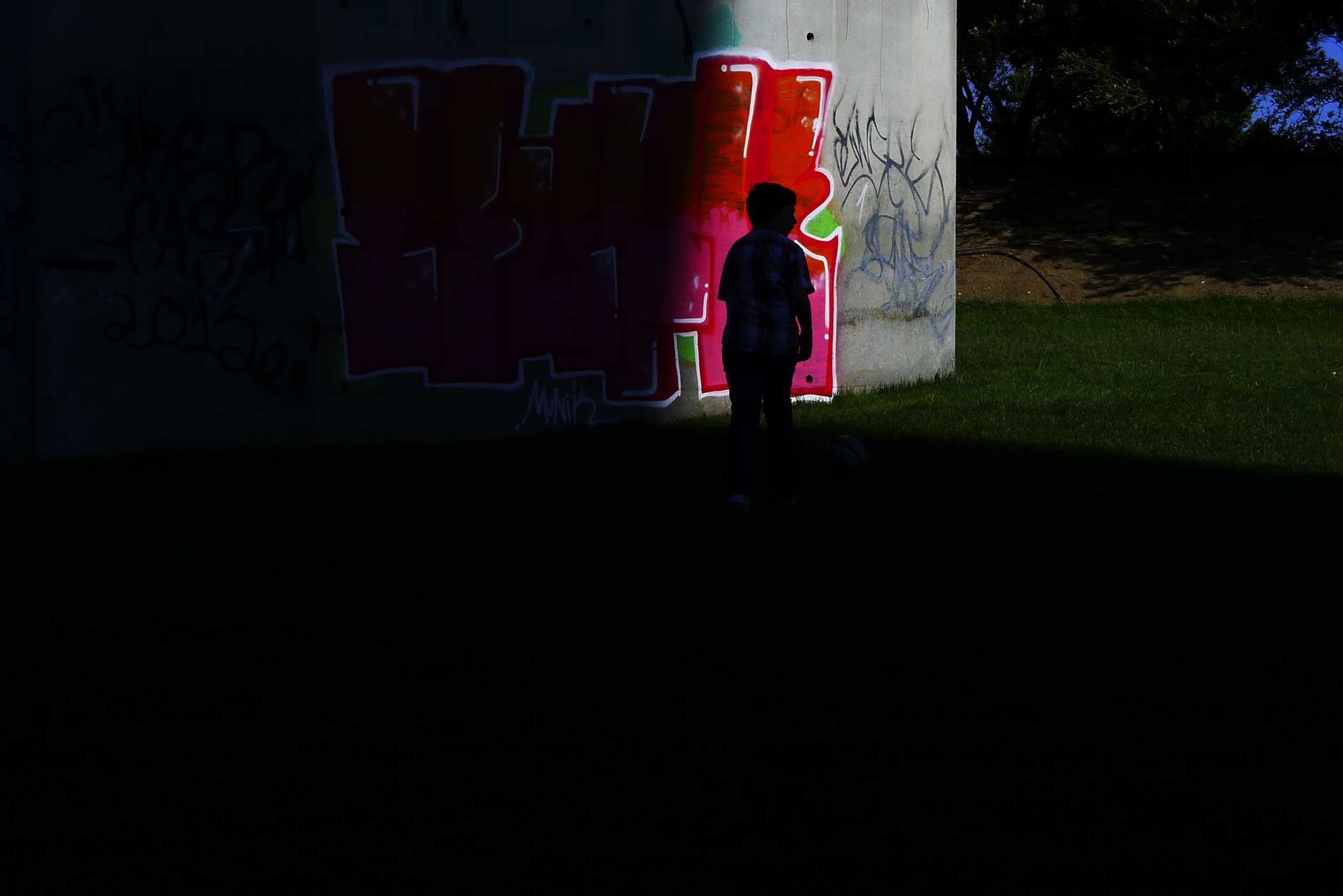 Picture of a kid in the dark looking for a friend to pass the ball while playing football